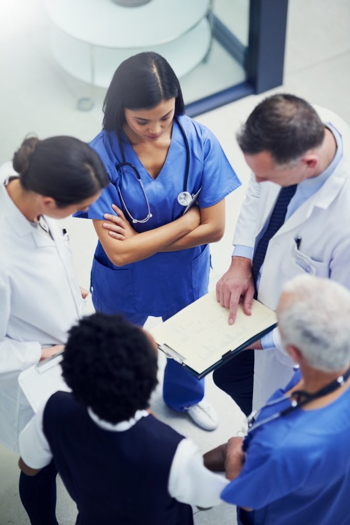 Medical professionals gathered around a clipboard